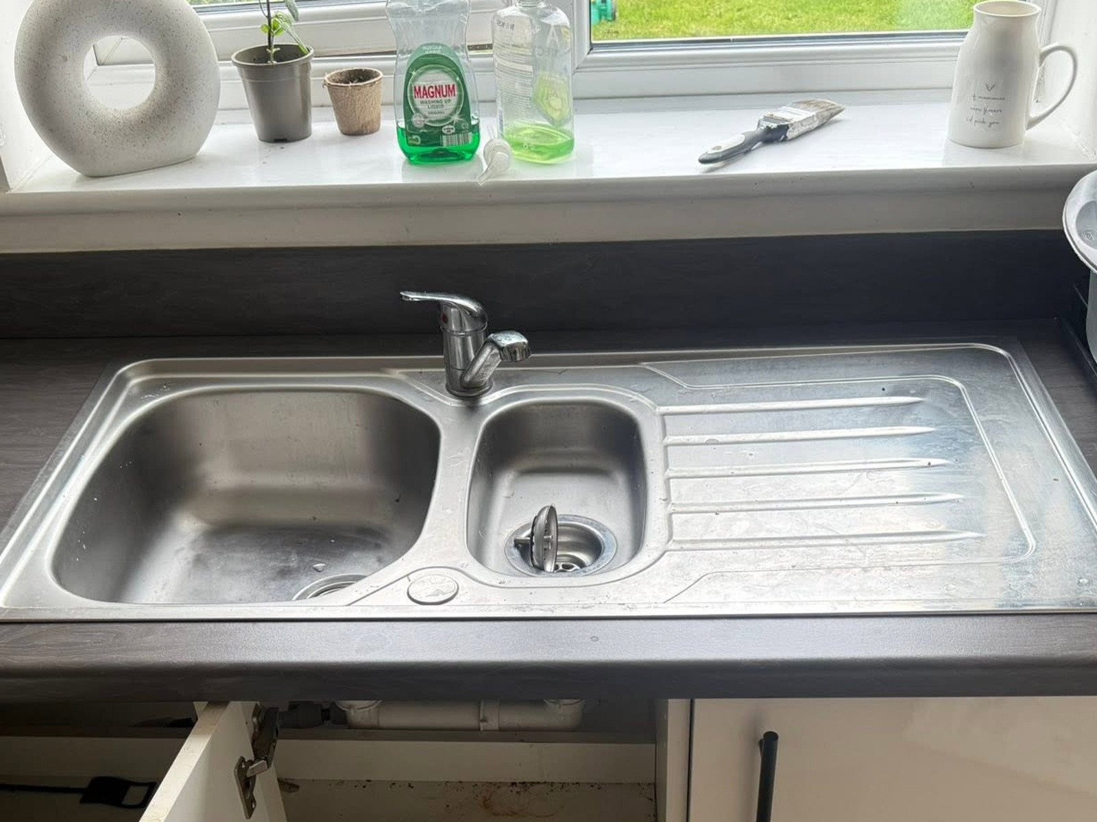 Old stainless steel kitchen sink and dated mixer tap before replacement