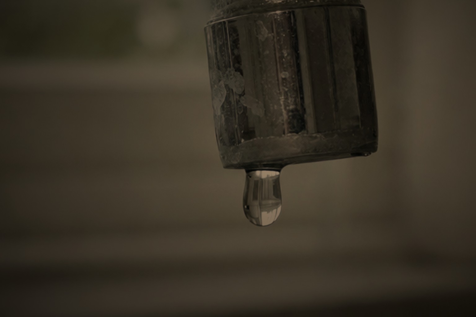 Dripping chrome tap with a water droplet forming at the spout